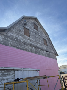 Exterior barn renovation with pink insulation panels and scaffolding by CJP Construction handyman services in Pierce, NE.