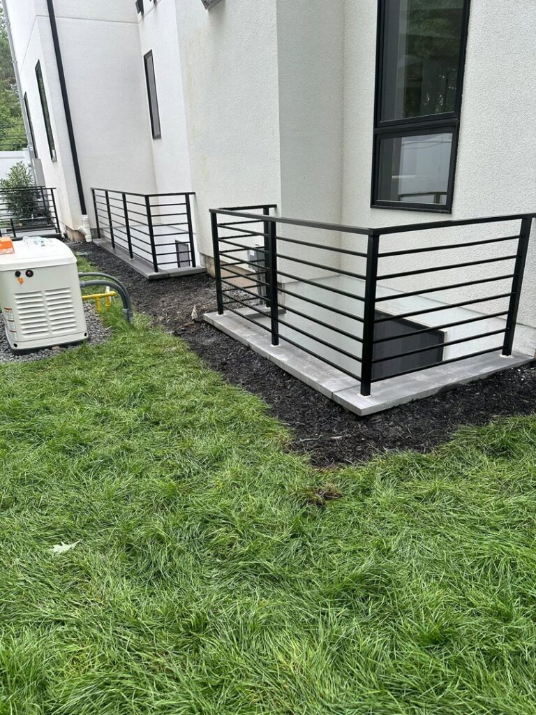 Black metal safety railings installed around exterior basement window wells by Advanced Welding All in One Fabrication LLC in Guttenberg, NJ.