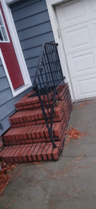 Exterior brick steps with a black metal railing leading to a house entrance, a handyman project by Coach Rose Painting Team in Norfolk, VA.