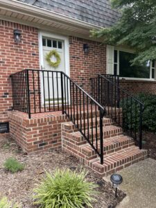 Black metal vertical bar railings installed on exterior brick steps by Custom Railing Solutions in Norfolk, VA