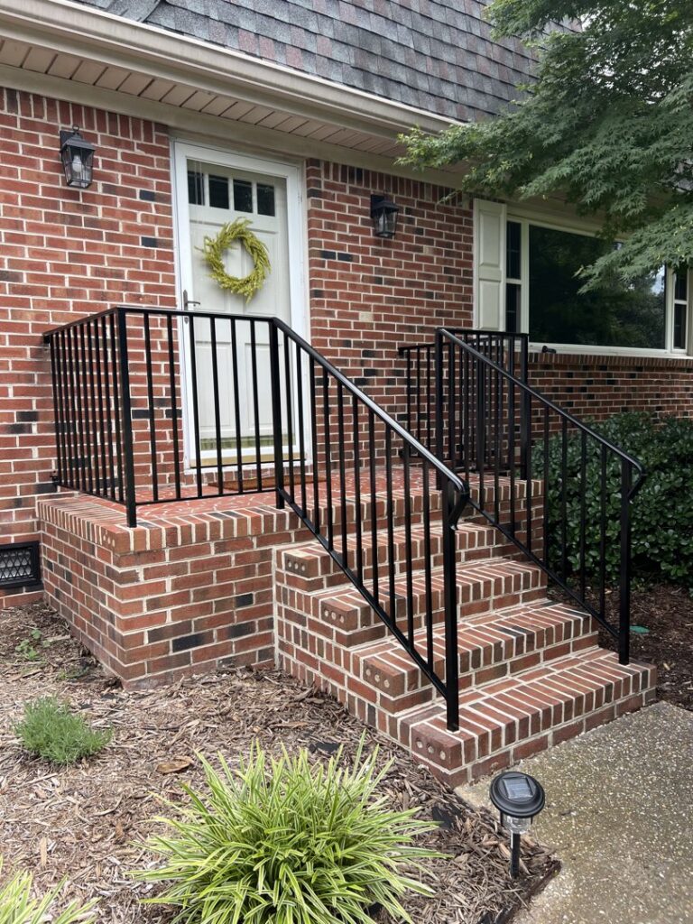 Black metal vertical bar railings installed on exterior brick steps by Custom Railing Solutions in Norfolk, VA