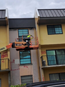 Worker in a boom lift performing exterior building maintenance for Vico Painting Contractors in Hialeah, FL