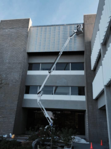 A worker in a boom lift performing exterior building maintenance for O'Byrne Painting & Contracting, Inc in Wayland, MA.