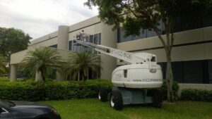 Worker in a boom lift performing exterior building painting for Vico Painting Contractors in Hialeah, FL