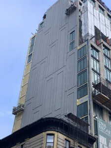 Workers on suspended platforms applying plaster to a building exterior by Sessa Plastering Corp. in Farmingdale, NY