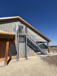 An exterior view of a building under construction, featuring a metal stairway and protective coverings, managed by Javier's Painting in San Angelo, TX.