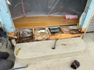 Exterior door frame repair and demolition showing exposed subfloor and insulation by Silhouette Builders, Inc. in Yorkville, IL