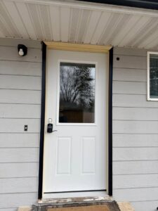 A newly installed white exterior door with black trim by Northeast SD Handyman in Watertown, SD.