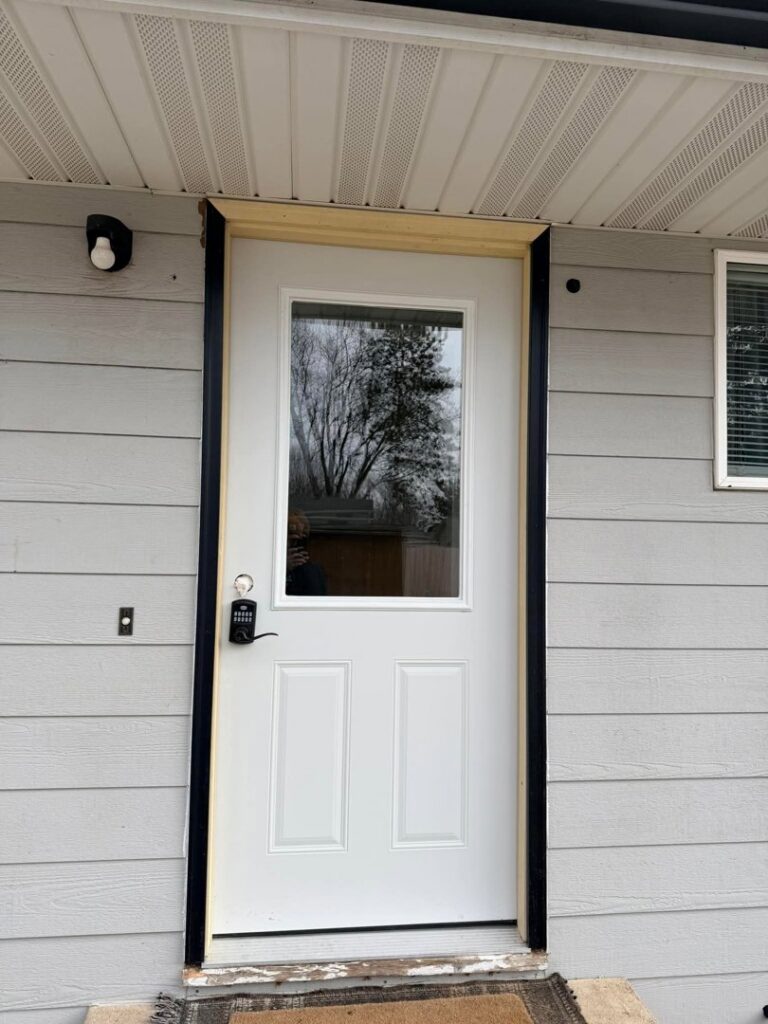 A newly installed white exterior door with black trim by Northeast SD Handyman in Watertown, SD.