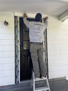 A handyman installing exterior trim around a door for JAC Home Improvement LLC in Danbury, CT.