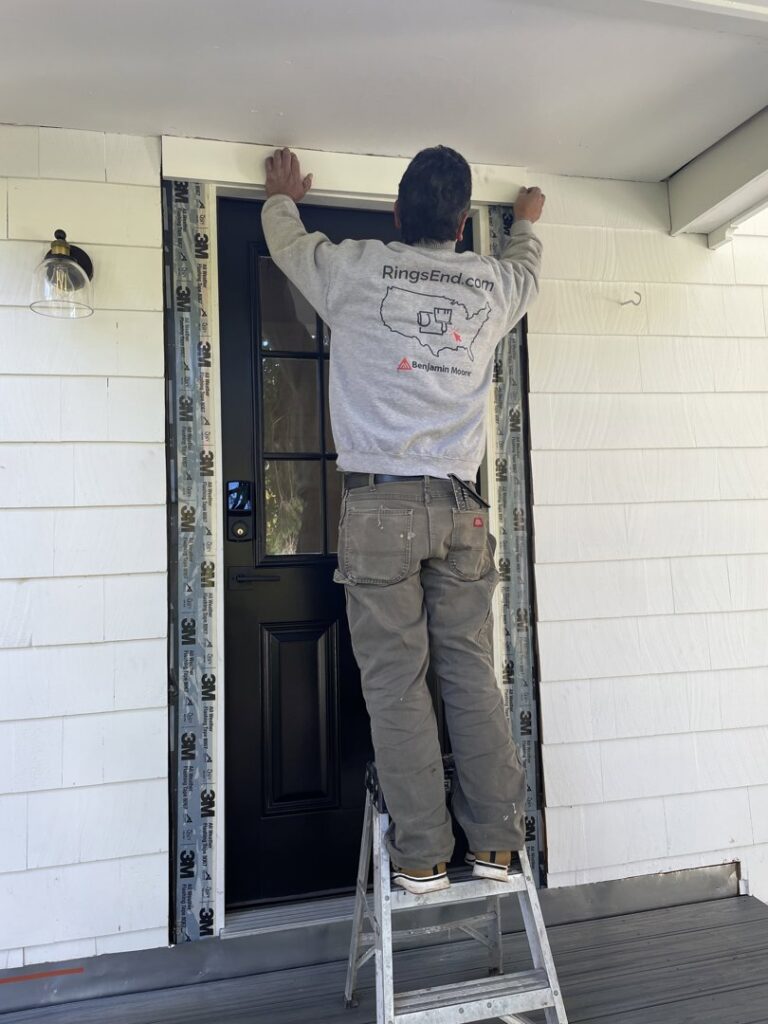 A handyman installing exterior trim around a door for JAC Home Improvement LLC in Danbury, CT.
