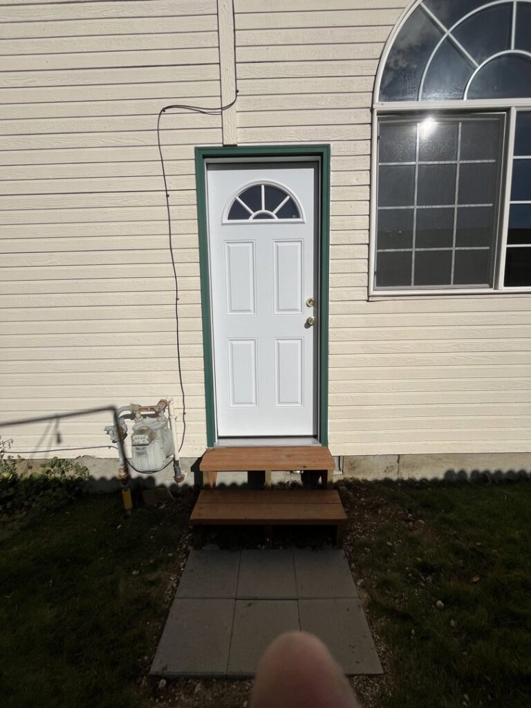 An exterior white door with green trim and newly installed wooden steps, completed by Forever Young Handyman Services in Boise, ID.