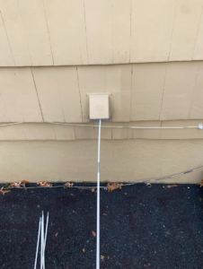 A handyman cleaning an exterior dryer vent with a specialized brush tool for DiEduardo Home Services LLC in Edison, NJ.