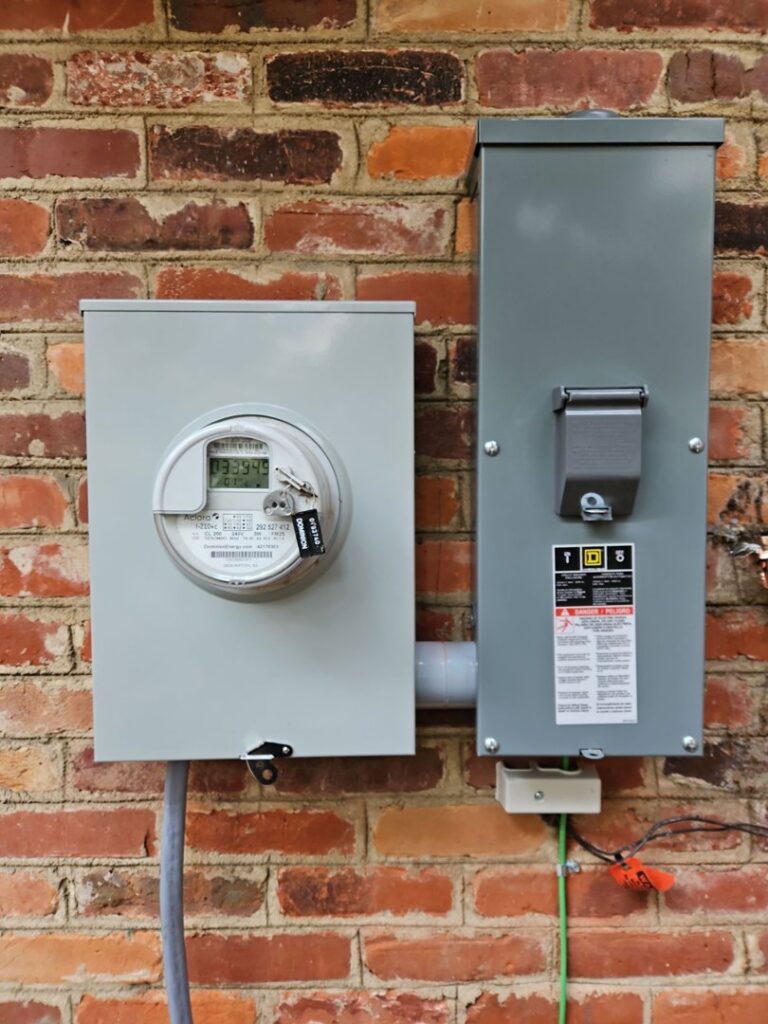 An exterior electrical meter and disconnect box installed on a brick wall by MorLite Electric in Newport News, VA.