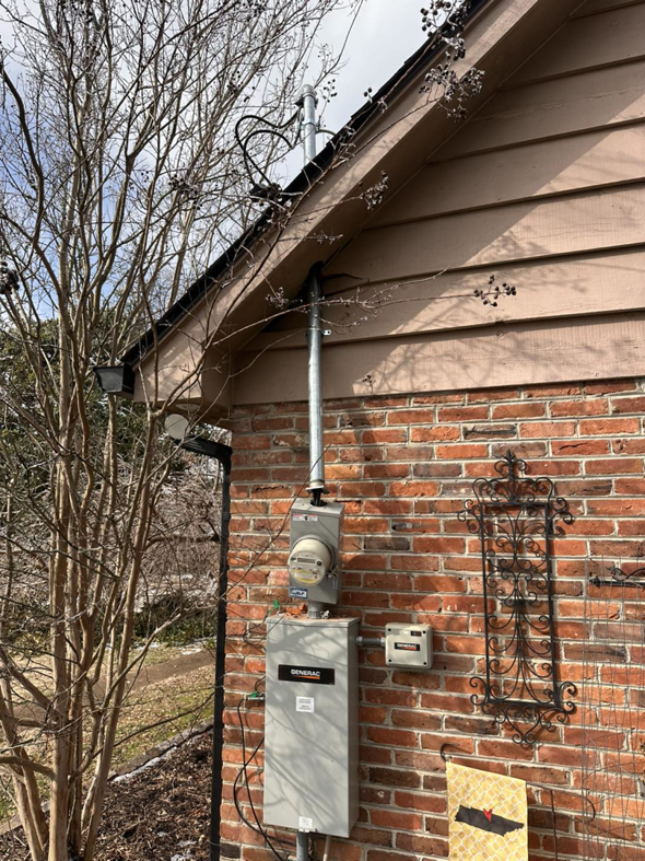 An exterior view of a house showing an electrical meter and Generac box installed by HHS Contractors in Providence Village, TX.