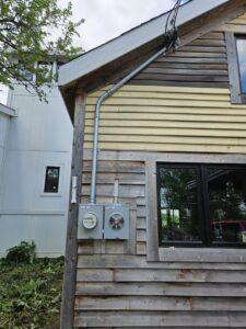 Exterior view of a house with two electrical meter boxes and conduit installed by Paramount Development in Milwaukee, WI.
