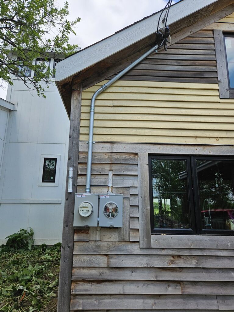 Exterior view of a house with two electrical meter boxes and conduit installed by Paramount Development in Milwaukee, WI.