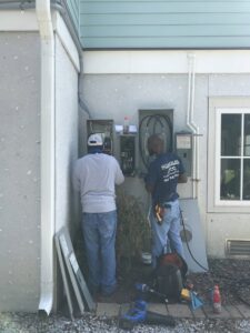 Two electricians working on exterior electrical panels for Carolina Custom Electric in Mount Pleasant, SC.