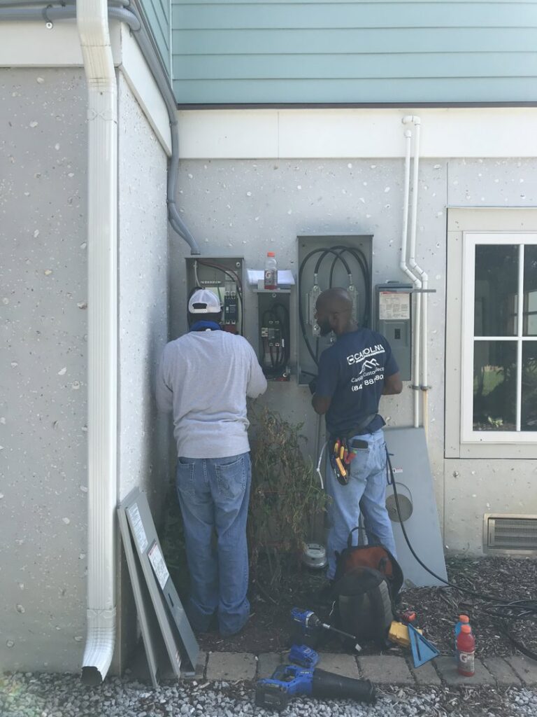 Two electricians working on exterior electrical panels for Carolina Custom Electric in Mount Pleasant, SC.