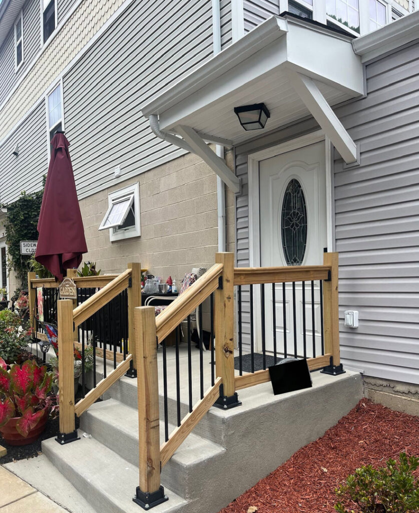 A newly renovated exterior entrance with a modern wooden railing and concrete steps by 3Rivers General Contracting in Pittsburgh, PA.