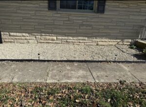 Exterior gravel landscaping with small outdoor lights along a house foundation by Lankford Dirt Works LLC in Indianapolis, IN.