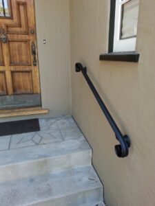 A decorative black wrought iron handrail installed on an exterior wall by Barry's Handyman Service in San Diego, CA.