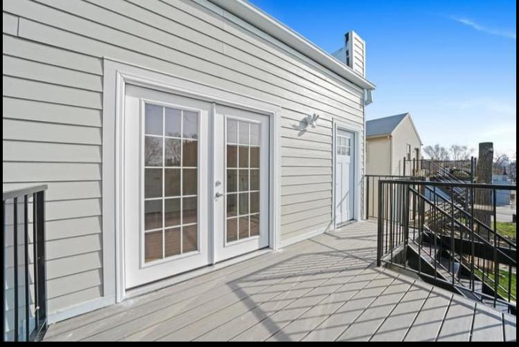 An exterior home renovation showing new siding, a spacious deck, and French doors by Revival Home Remodeling in Chicago, IL.