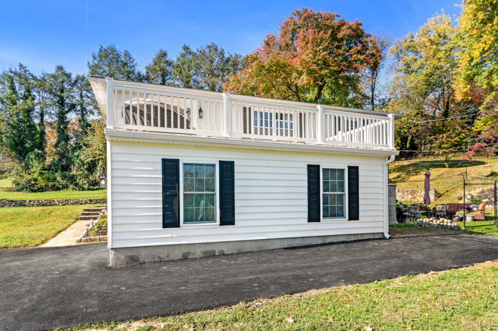 Exterior view of a white house with black shutters and a newly built rooftop deck by Total Craftsmen in Towson, MD