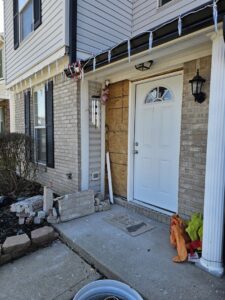 Exterior home repair at the front entrance with boarded-up section and broken bricks by Urban Restoration, LLC in Indianapolis, IN