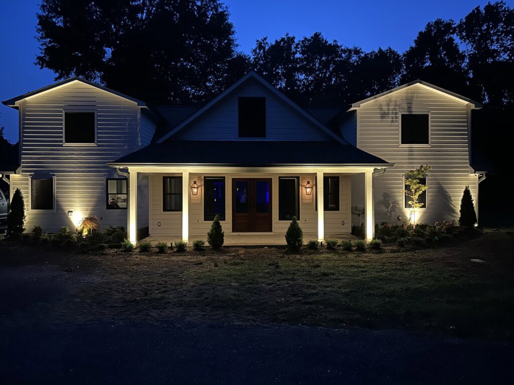 Exterior of a house at night with new landscape lighting installed by CMT Construction LLC in Columbia, MO.
