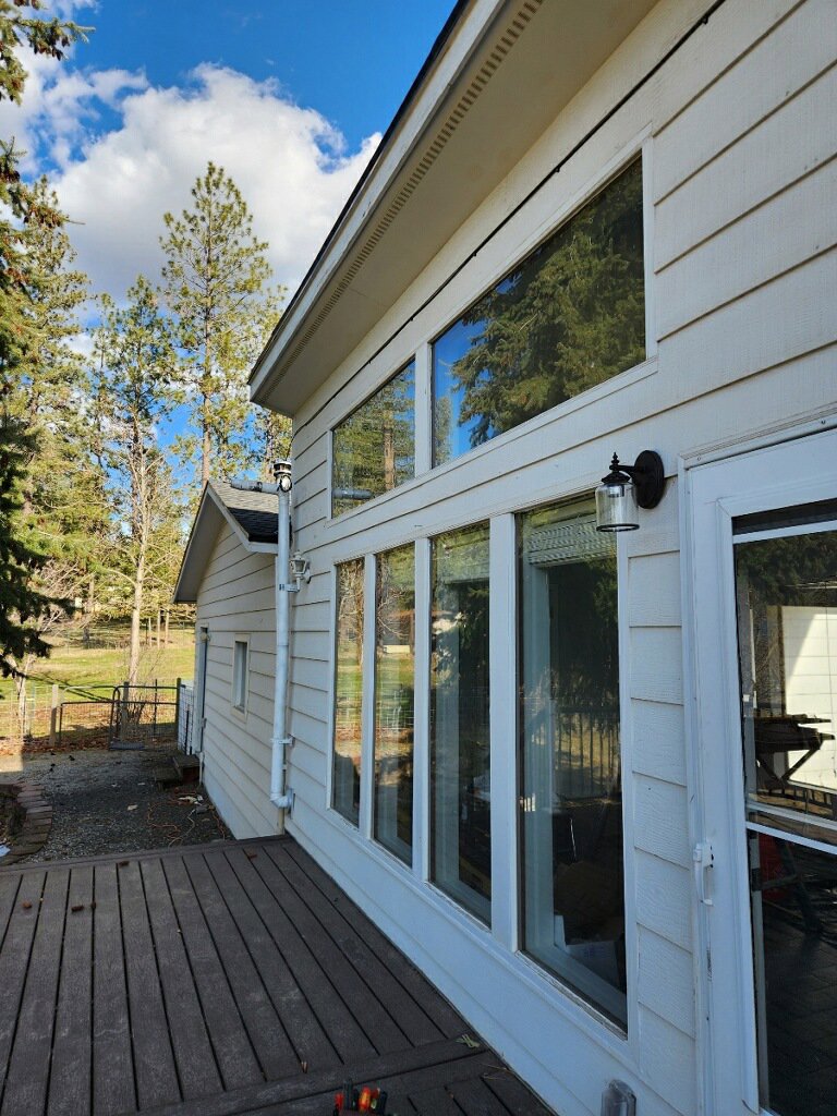 Exterior of a house with large windows and deck, featuring an installed outdoor light fixture by Epic Electric, Heating, Cooling & Plumbing in Spokane, WA