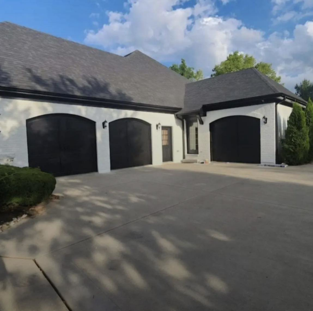 Exterior house painting with white brick and black garage doors by Rock Creek Renovation and Painting in Waynesville, OH