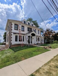 Exterior house painting in progress with painters on ladders by Roche Painting in Allentown, PA.