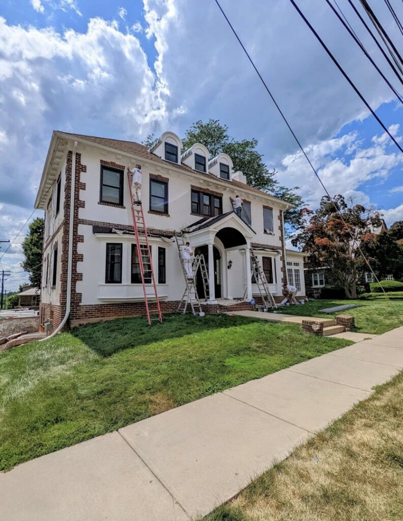 Exterior house painting in progress with painters on ladders by Roche Painting in Allentown, PA.