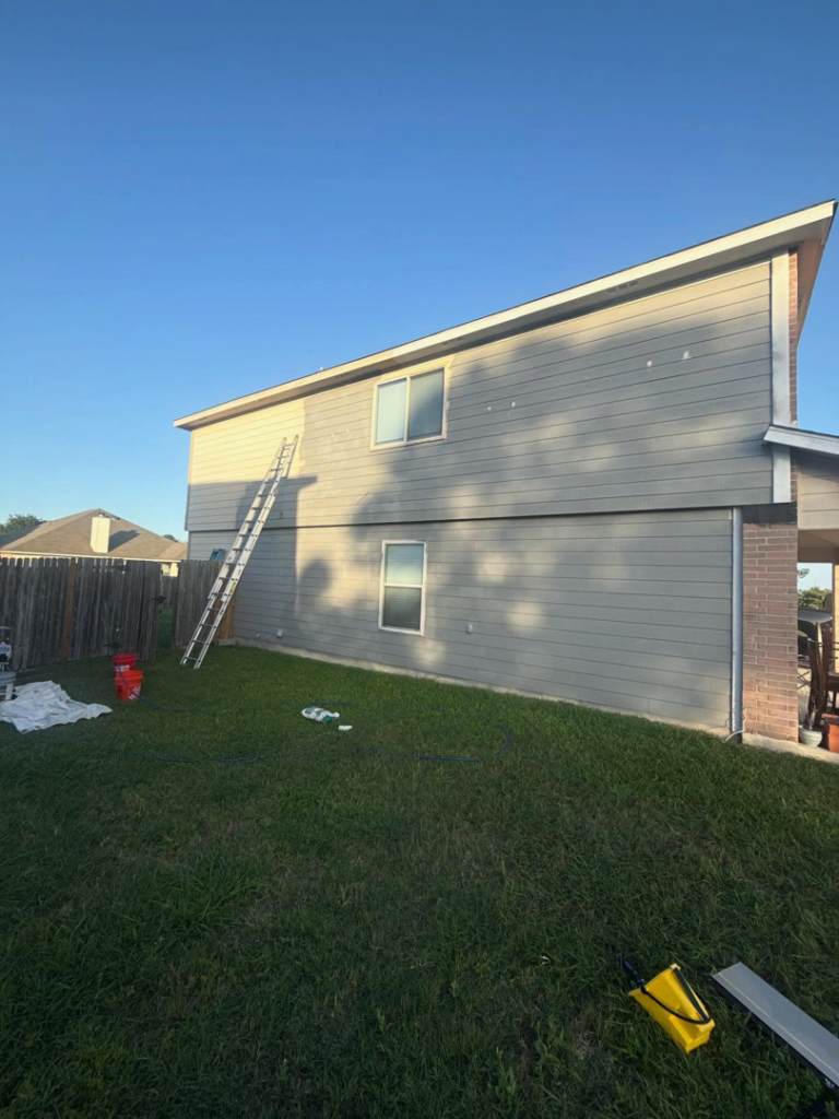 Exterior house painting in progress with ladders and paint buckets by The First Choice Painting in San Antonio, TX