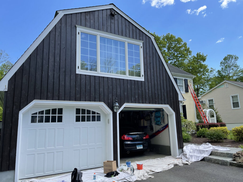 An exterior house painting job in progress with dark siding and white trim, performed by GO Painting in New Haven, CT
