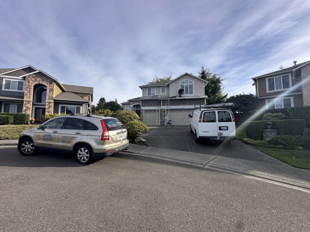 Exterior house painting in progress with ladders and a work van by J&R Buezo Painting Services LLC in Everett, WA