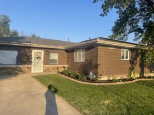 The exterior of a house with brown siding, windows taped off for painting or siding work, by Knutson's Property Maintenance Llc in Williston, ND.