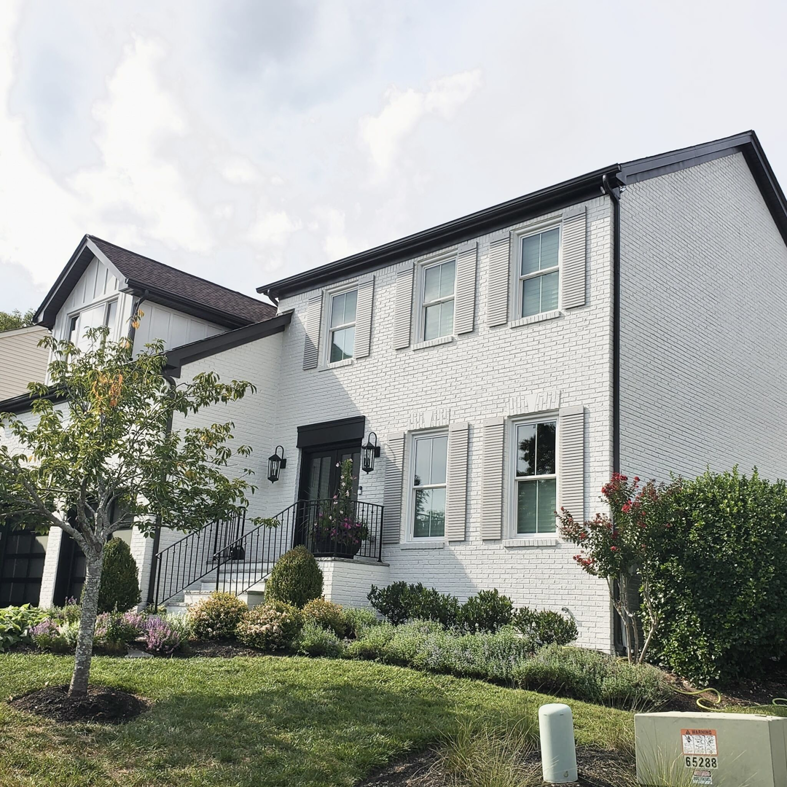 Exterior view of a newly painted white brick house with dark trim, a project completed by Prestige Remodeling Solutions in Antioch, TN