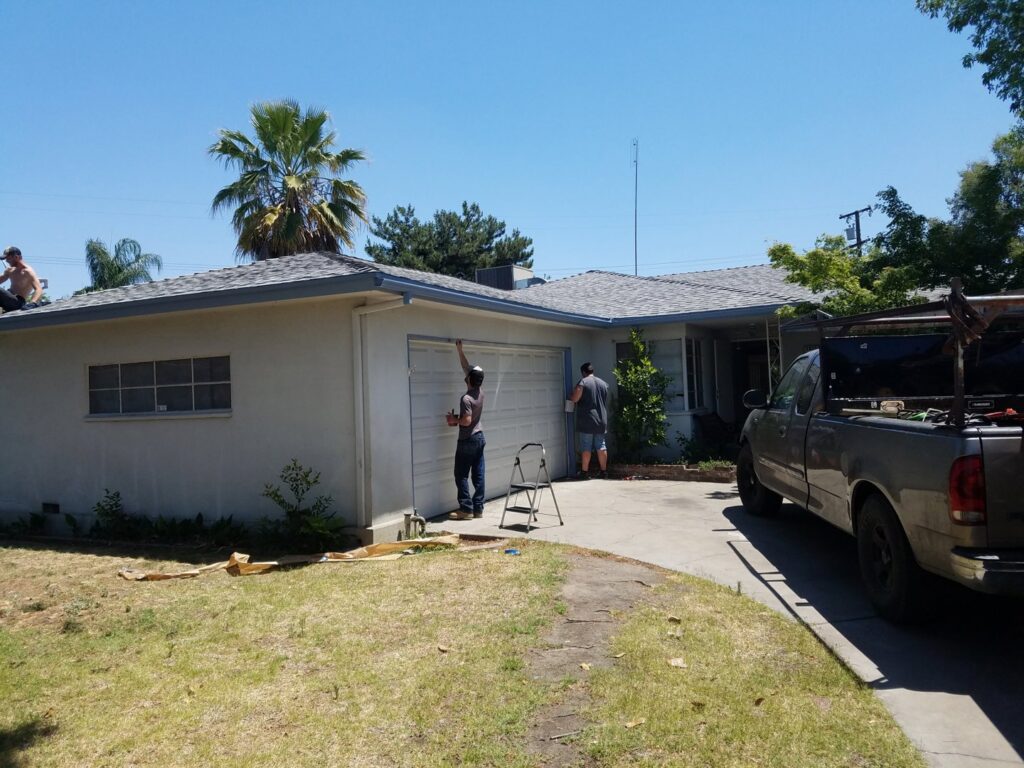 Contractors performing exterior house painting and roof work on a residential property by Red Gator Maintenance in Fresno, CA.