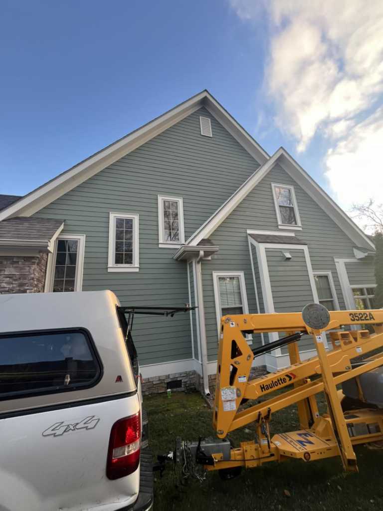 A lift and truck next to a house with new siding, indicating exterior painting or renovation by PrimeTime Painting in Bowling Green, KY.