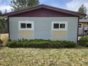 Exterior house showing new windows and siding work in progress, with a person on a ladder, by Stephen Appel Handyman/Contractor in Meridian, ID.