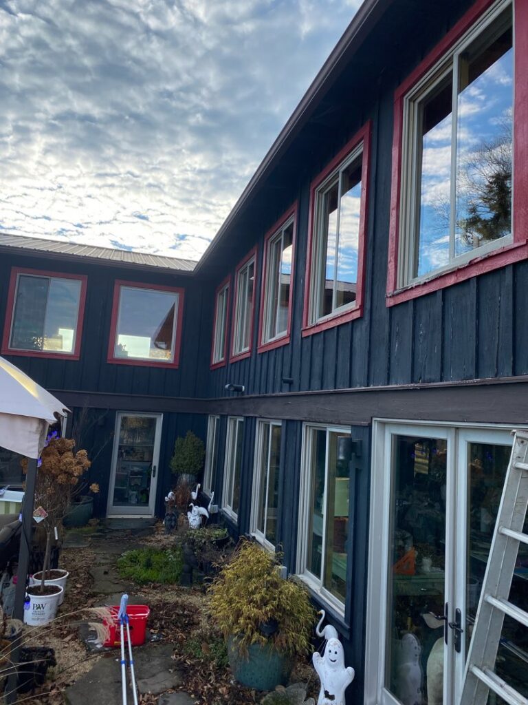 The exterior of a house with dark siding and red trim, with a ladder suggesting painting or repair work by In Goode Hands LLC in Beckley, WV.