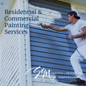 A professional painting the exterior siding of a house with a paint sprayer for S&M Painting and Drywall in Carmel, IN.