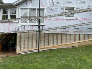 Exterior of a house under remodeling with siding removed and ladders, by Remodeling by Simplified Solutions in Saint Charles, MO