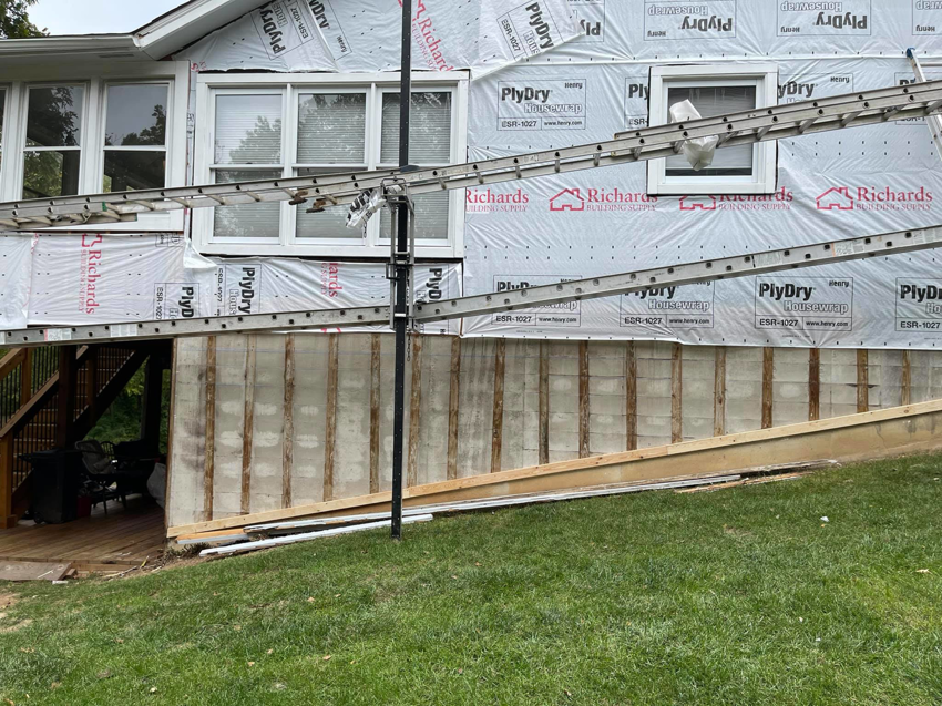 Exterior of a house under remodeling with siding removed and ladders, by Remodeling by Simplified Solutions in Saint Charles, MO