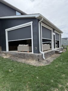Exterior of a house with dark siding and newly installed retractable screens on a patio by M&M Home Builders, LLC in Richmond, VA.