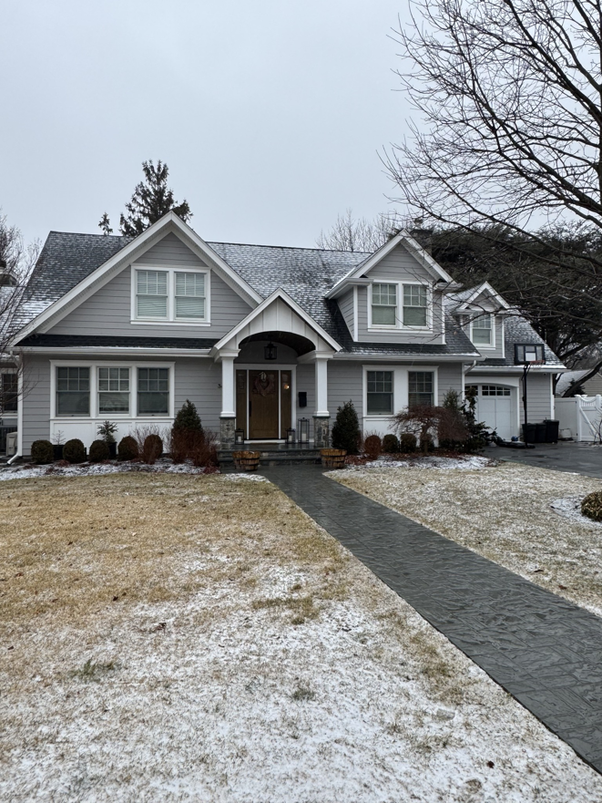 The exterior of a well-maintained house with a light dusting of snow, showcasing home improvements by Tarr's Home Improvements in Franklin Square, NY.