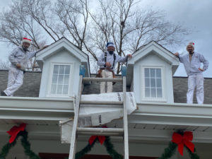 Three handymen working on the exterior of a house, near dormers and gutters, for Custom Remodeling Inc. in Houston, TX.