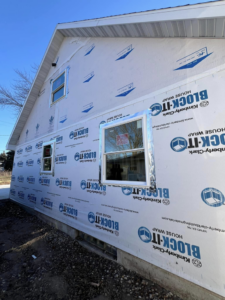Exterior of a house with new house wrap and window installation by Sandoval Contracting & Remodeling in Menasha, WI.